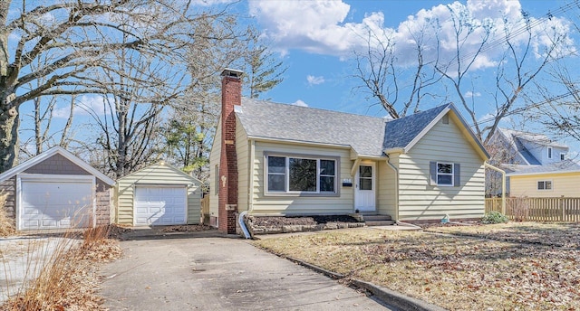 view of front facade with an outbuilding, a chimney, a shingled roof, entry steps, and a garage