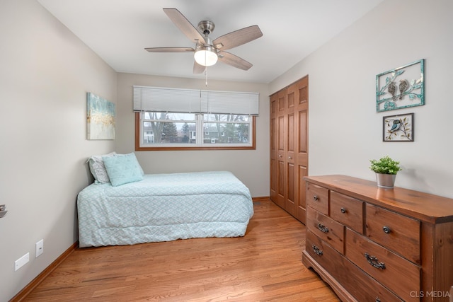 bedroom featuring a closet, baseboards, ceiling fan, and light wood finished floors