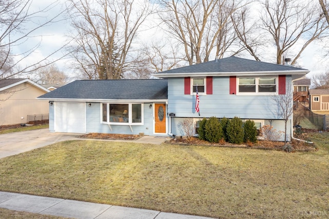 tri-level home featuring an attached garage, a shingled roof, concrete driveway, and a front yard