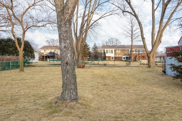 view of yard featuring a trampoline and fence