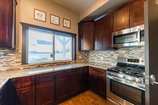 kitchen featuring light stone countertops, stainless steel appliances, dark wood-style flooring, and backsplash