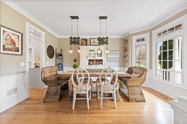 dining area with light wood-style floors, ornamental molding, and visible vents