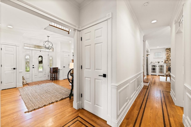 entryway with crown molding, a wainscoted wall, an inviting chandelier, a decorative wall, and recessed lighting