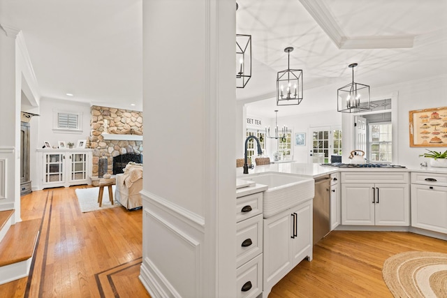 bar with a sink, light wood-style flooring, gas stovetop, and a notable chandelier