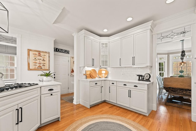 kitchen featuring light wood-type flooring, ornamental molding, recessed lighting, and light countertops