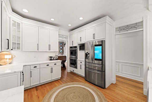 kitchen featuring glass insert cabinets, light wood-style flooring, stainless steel appliances, and white cabinetry