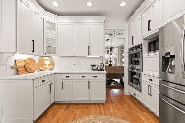 kitchen with white cabinets, stainless steel appliances, glass insert cabinets, and light wood finished floors