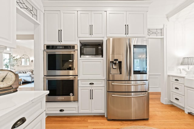 kitchen featuring crown molding, light wood-style floors, appliances with stainless steel finishes, and white cabinets