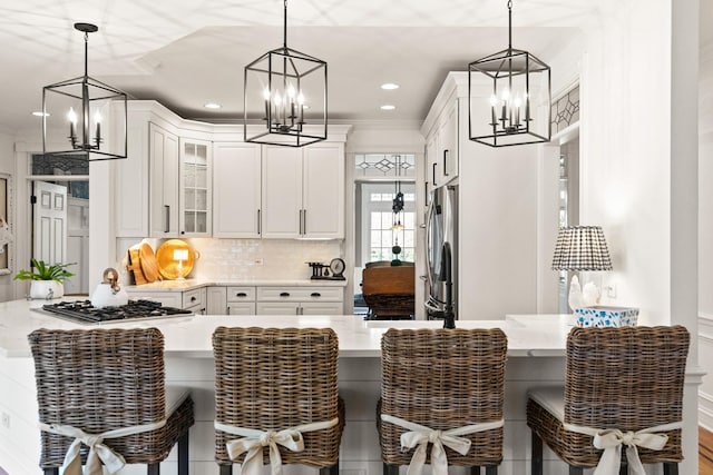kitchen with an inviting chandelier, appliances with stainless steel finishes, white cabinets, and glass insert cabinets