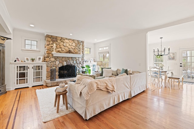 living room with ornamental molding, wood finished floors, a chandelier, and a fireplace