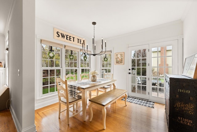 dining room with crown molding, light wood finished floors, plenty of natural light, and a notable chandelier
