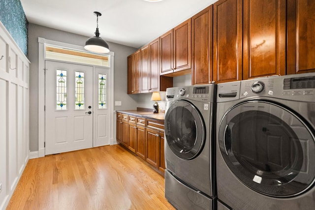 laundry area featuring light wood-style floors, washer and clothes dryer, cabinet space, and baseboards