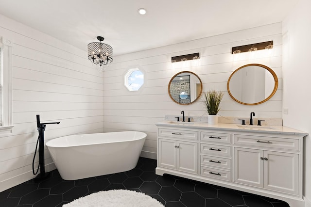 bathroom featuring double vanity, a sink, a freestanding tub, and tile patterned flooring