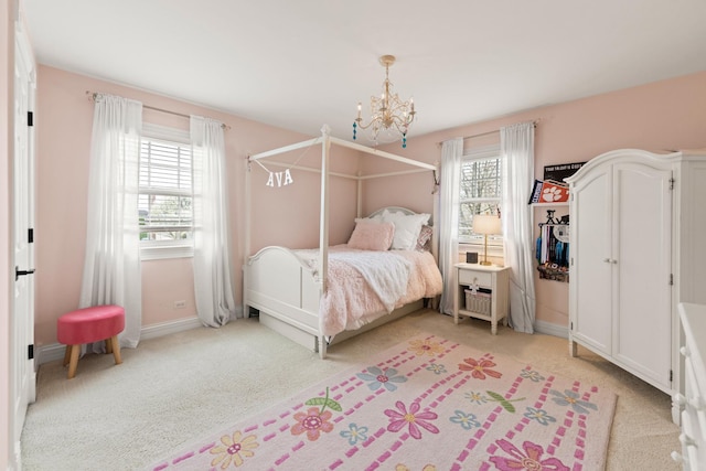 bedroom with light colored carpet, baseboards, and an inviting chandelier