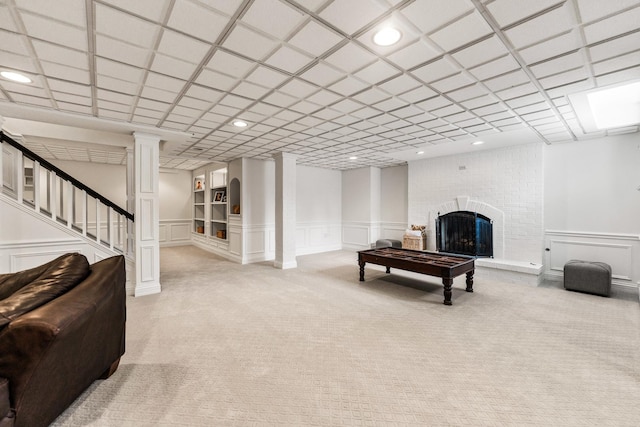living room with light colored carpet, wainscoting, a decorative wall, and a fireplace