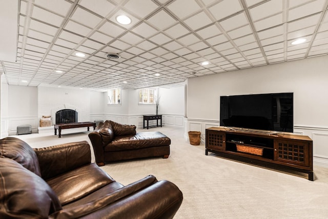 living area with carpet floors, a fireplace, a wainscoted wall, and a decorative wall