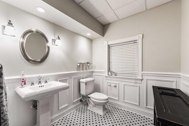 bathroom featuring wainscoting, a decorative wall, and toilet