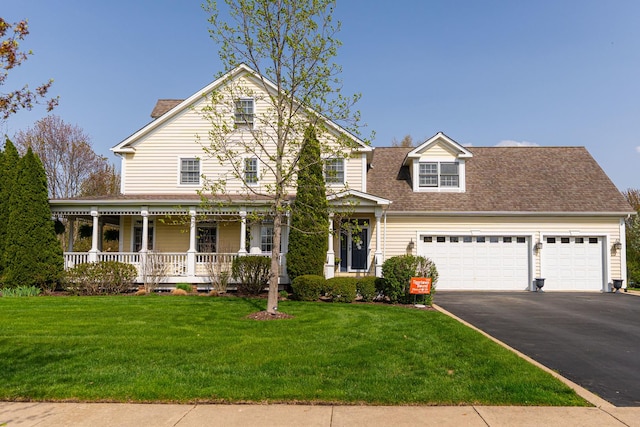 view of front of property with covered porch, a garage, a front yard, and aphalt driveway