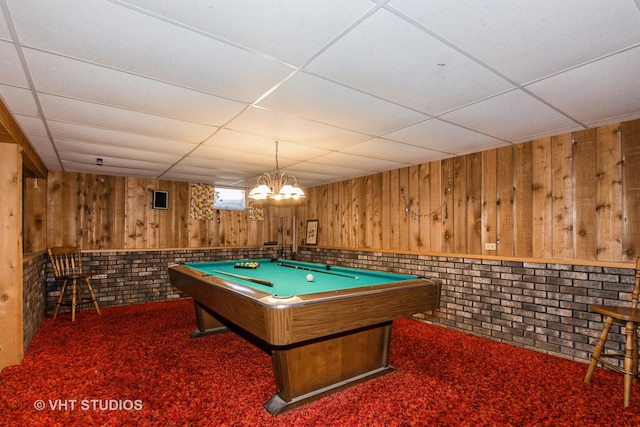 game room with a drop ceiling, wooden walls, and carpet flooring