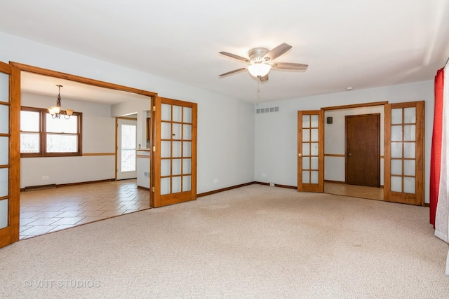 carpeted spare room with ceiling fan with notable chandelier, french doors, visible vents, and baseboards