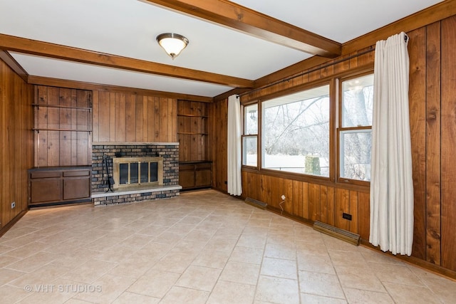 unfurnished living room featuring beam ceiling, visible vents, wood walls, and a brick fireplace