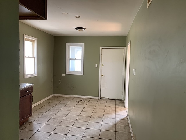 doorway featuring a healthy amount of sunlight, baseboards, and light tile patterned flooring