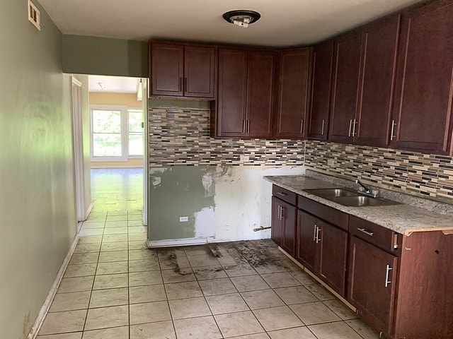 kitchen with tasteful backsplash, light countertops, visible vents, a sink, and baseboards