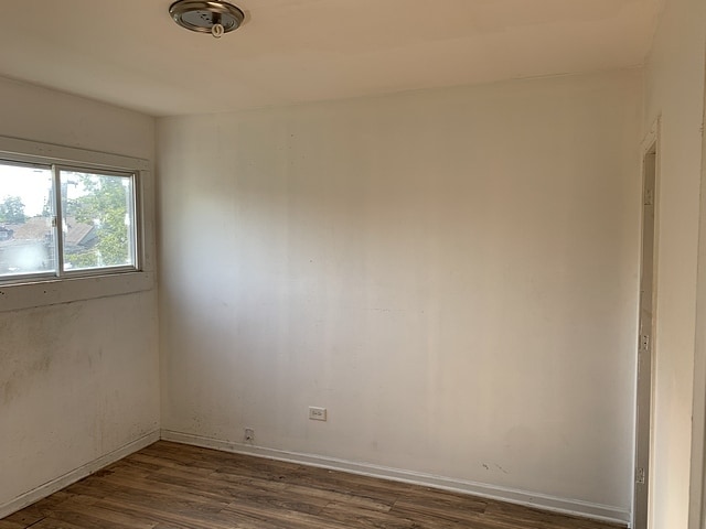 spare room featuring dark wood-type flooring and baseboards