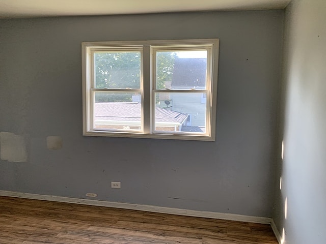 spare room with baseboards and wood finished floors