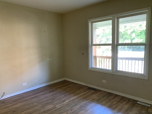 unfurnished room featuring visible vents, baseboards, and wood finished floors