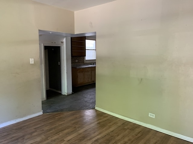 spare room featuring dark wood-style flooring and baseboards