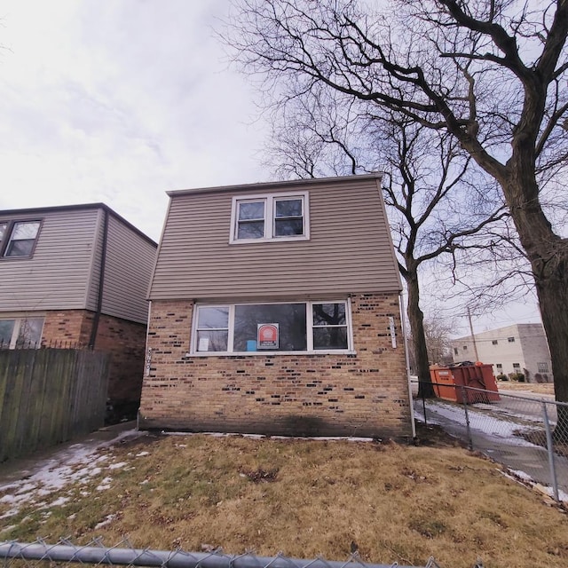 view of front of home with brick siding and fence