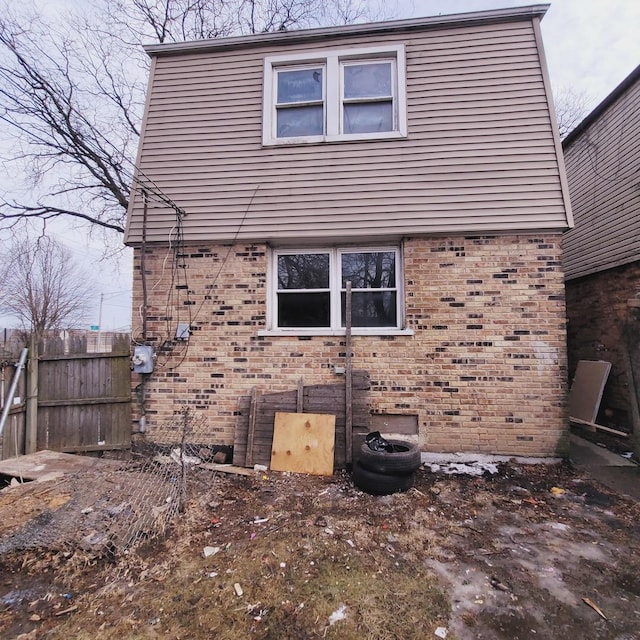 view of side of property featuring fence and brick siding