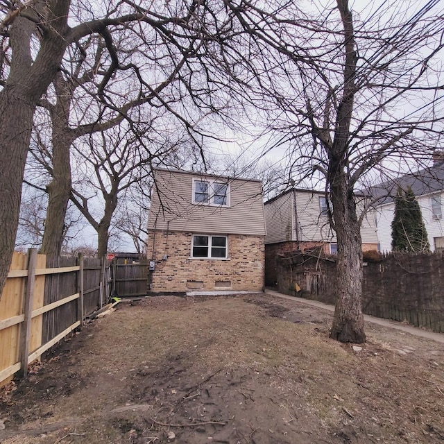 back of property with brick siding and a fenced backyard