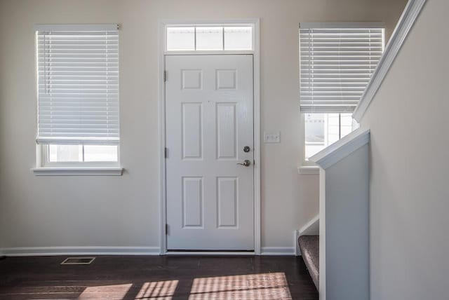 entrance foyer with visible vents, dark wood finished floors, stairway, and baseboards