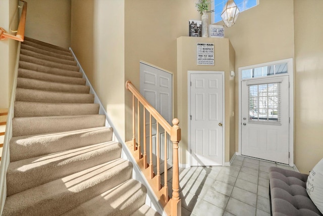 foyer entrance with tile patterned flooring, a towering ceiling, baseboards, and stairs