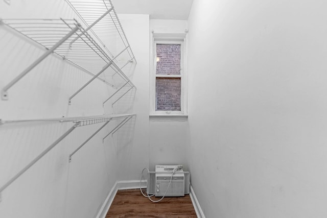 walk in closet with a wall mounted AC and dark wood finished floors