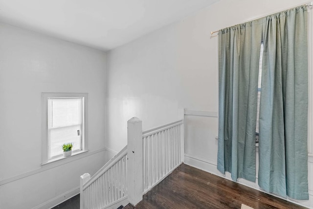 hallway featuring a wainscoted wall, an upstairs landing, and wood finished floors