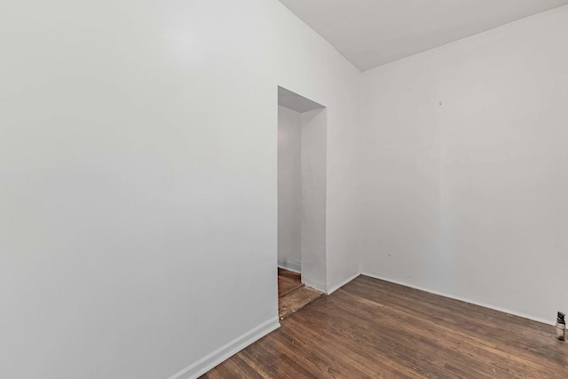 spare room with baseboards and wood finished floors