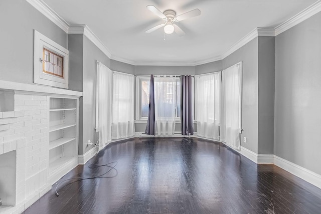 spare room featuring ceiling fan, built in shelves, wood finished floors, baseboards, and ornamental molding