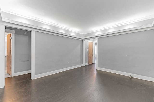 empty room with baseboards, wood finished floors, and ornamental molding