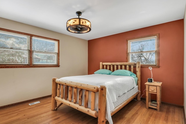 bedroom featuring multiple windows, light wood-type flooring, and baseboards