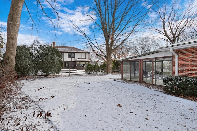 snowy yard featuring a sunroom