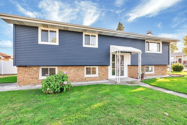 rear view of house featuring a yard, brick siding, and fence