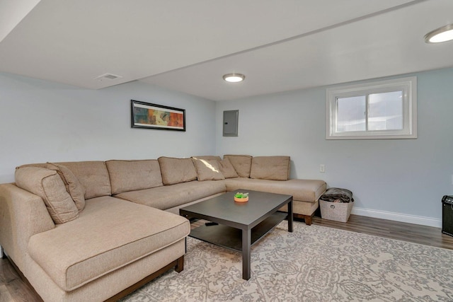 living area featuring visible vents, wood finished floors, electric panel, and baseboards