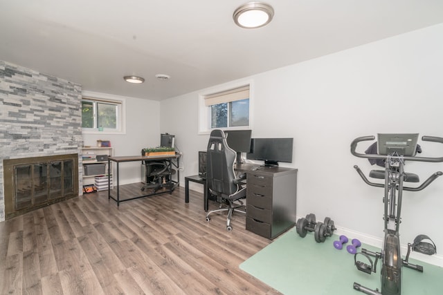 home office featuring a tiled fireplace, baseboards, and wood finished floors