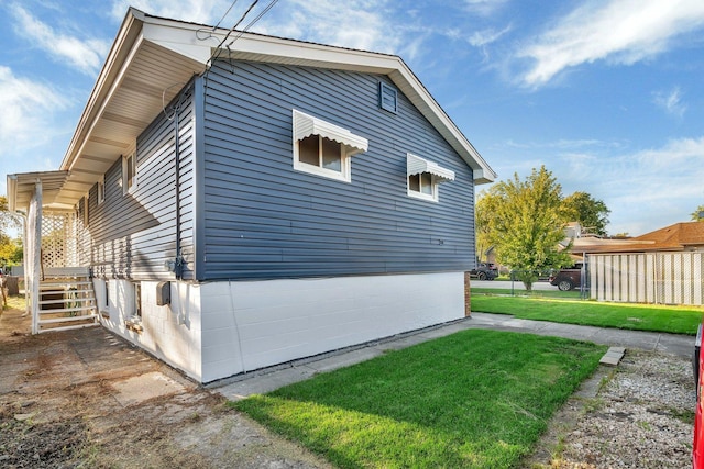 view of side of home featuring fence and a lawn