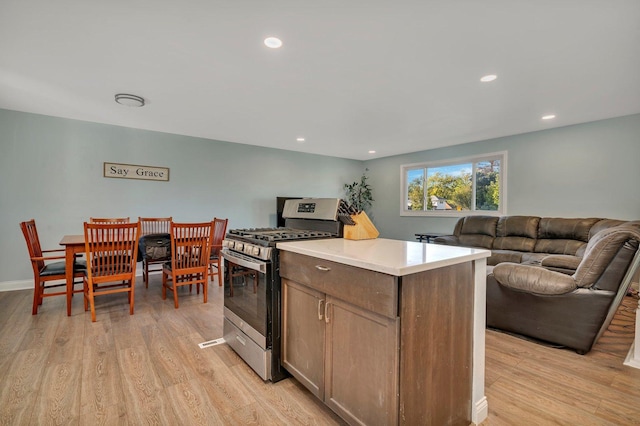 kitchen with light wood finished floors, light countertops, stainless steel range with gas stovetop, and a center island