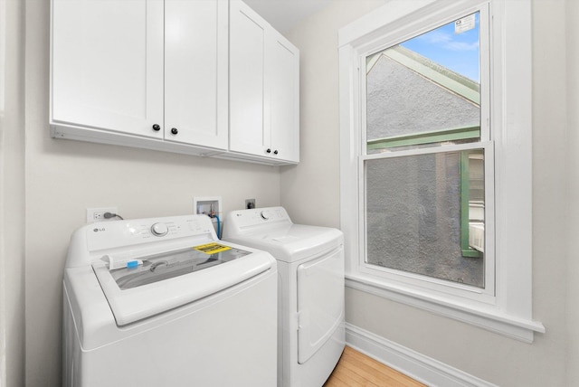 clothes washing area featuring cabinet space, washer and dryer, light wood-style flooring, and baseboards