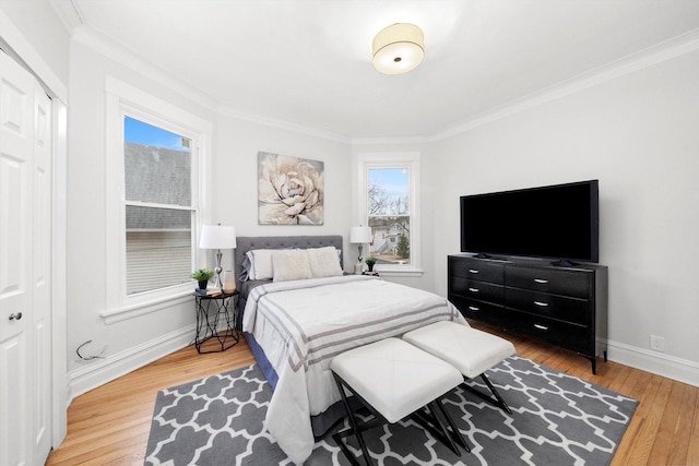 bedroom featuring a closet, light wood-style flooring, baseboards, and ornamental molding